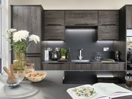 A kitchen with cabinets, sink, kettle, and a bowl with salad at Costal Lodge at Seaham Hall, Seaham