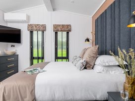 A bedroom with a bed and wall-mounted TV at Costal Lodge at Seaham Hall in Seaham