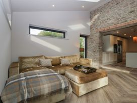 A living room with a sofa and a view of the kitchen at 3 bed property