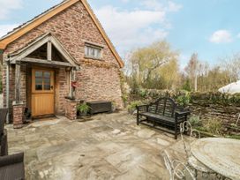An outdoor patio with a stone wall and bench at a 1 bed property in Usk