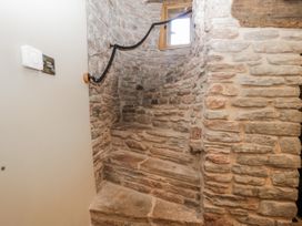 A staircase with stone walls and a window at 1 bed property Usk