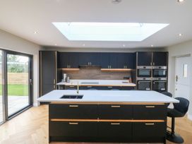 A kitchen with black cabinets and a central island at Angorfa in Pentraeth