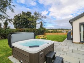 A hot tub and seating area in a garden at Angorfa in Pentraeth