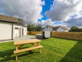 A garden with a table and a spa at Angorfa in Pentraeth