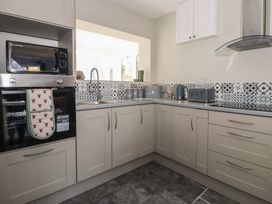 A kitchen with a microwave, oven, sink, and kettle at Forget Me Not Cottage in Hull