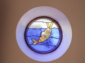 A stained glass window depicting a fish jumping out of water at Arum, Portland Bill