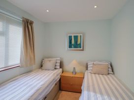 A bedroom with two beds and a lamp at Arum in Portland Bill