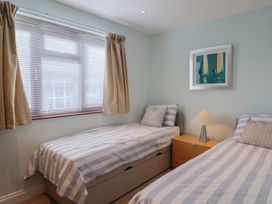 A bedroom with two beds and a lamp at Arum in Portland Bill