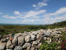 A view of the sea and grassland with a stone wall at Goetra