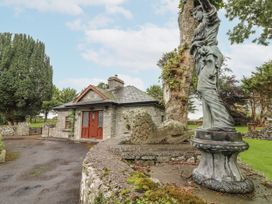 A stone cottage with a lion statue and a female statue at Coole Gate Lodge in Gort, County Galway