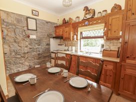 A kitchen with wooden cabinets and a dining table at Coole Gate Lodge, Gort, County Galway
