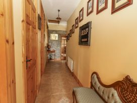 A hallway with framed pictures and a chair at Coole Gate Lodge in Gort, County Galway