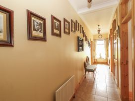 A hallway with framed photographs and a bench at Coole Gate Lodge, Gort, County Galway