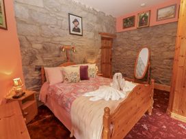A bedroom with a bed and stone wall at Coole Gate Lodge, Gort, County Galway