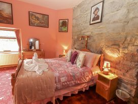 A bedroom with a bed and side table at Coole Gate Lodge, Gort, County Galway