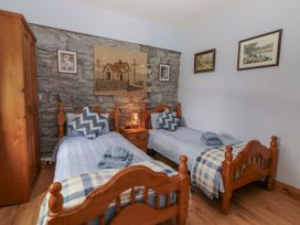 A bedroom with two beds and a wardrobe at Coole Gate Lodge in Gort, County Galway