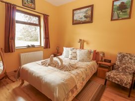 A bedroom with a bed and a chair at Coole Gate Lodge, Gort, County Galway