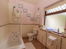 A bathroom with a bathtub, shower, toilet, and mirror at Coole Gate Lodge, Gort, County Galway