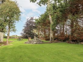 A garden with trees and a stone wall at Coole Gate Lodge in Gort, County Galway