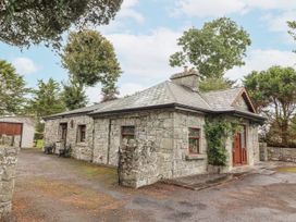 A stone cottage with trees in the background at Coole Gate Lodge in Gort, County Galway