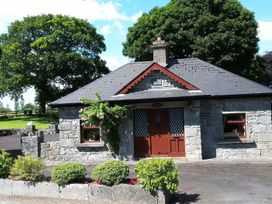 A stone cottage with a red door and windows at Coole Gate Lodge, Gort, County Galway