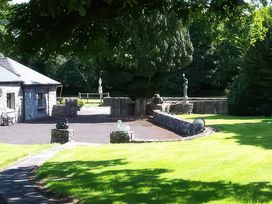 An outdoor area with sculptures and a stone building at Coole Gate Lodge, Gort, County Galway