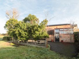 An exterior view of a house surrounded by trees and a fence at Wellinghill Cottage at Wellinghill House Charlton Kings