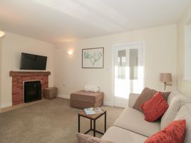 A living room with a television and fireplace at Wellinghill Cottage at Wellinghill House in Charlton Kings
