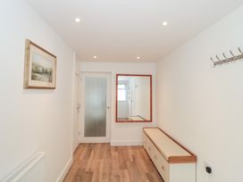 A hallway with a mirror, coat hooks, and a bench at Wellinghill Cottage at Wellinghill House in Charlton Kings