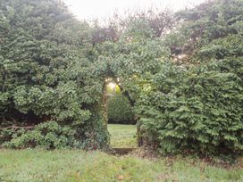 A garden with a gate surrounded by hedges at Wellinghill Cottage at Wellinghill House, Charlton Kings