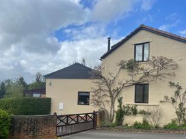 A house with a gate and surrounding plants at Wellinghill Cottage in Charlton Kings