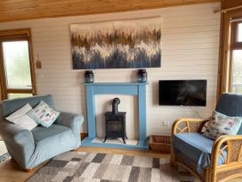 A living room with a fireplace and a television at Lamorna in Sennen