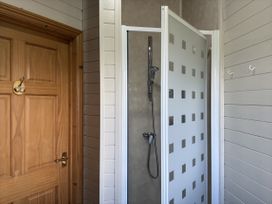 A bathroom featuring a shower with a door and a wooden door at Lamorna, Sennen