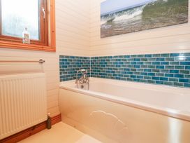 A bathroom with a bathtub and mosaic tiles at Lamorna in Sennen