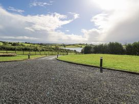 A gravel driveway leading to a view with trees and a lake at Woodlawn Retreat in Portanure near Lough Gowna