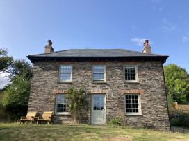 A house with stone exterior and chairs in front at Treovis Cottage Callington