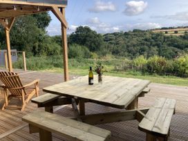 A table with chairs and a bottle on a deck at Treovis Cottage in Callington