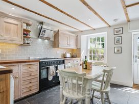 A kitchen with cabinets and a table at Treovis Cottage in Callington
