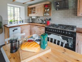 A kitchen with oven, sink, and dining table at Treovis Cottage in Callington