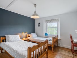 A bedroom with two beds and a desk at Treovis Cottage in Callington