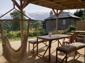 An outdoor seating area with a hammock and table at Treovis Cottage in Callington