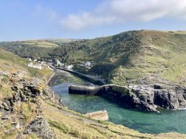 A coastal view with water, cliffs, and buildings at Treovis Cottage in Callington