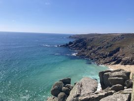 A view of the ocean and beach with rocky coastline at Treovis Cottage Callington