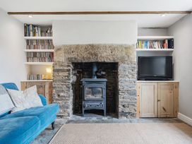 A living room with a wood stove and shelves at Treovis Cottage in Callington