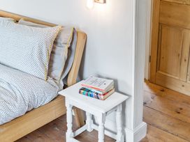 A bedroom with a bed and books on a nightstand at Treovis Cottage Callington
