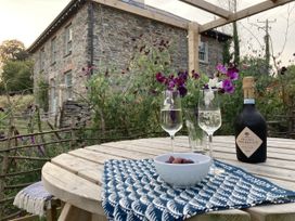 An outdoor setting with glasses and a bottle on a table at Treovis Cottage in Luckett near Kelly Bray