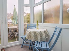 A conservatory with a table and chairs, a wine bottle and glasses at Cherry Pip, Charmouth
