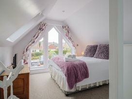 A bedroom with a bed and windows at Cherry Pip in Charmouth