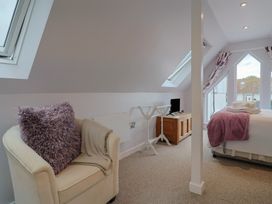 A bedroom with a bed and a chair at Cherry Pip in Charmouth