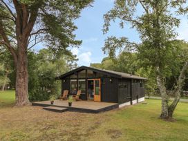 A cabin with a deck surrounded by trees at Blue Pine Lodge in Dornoch